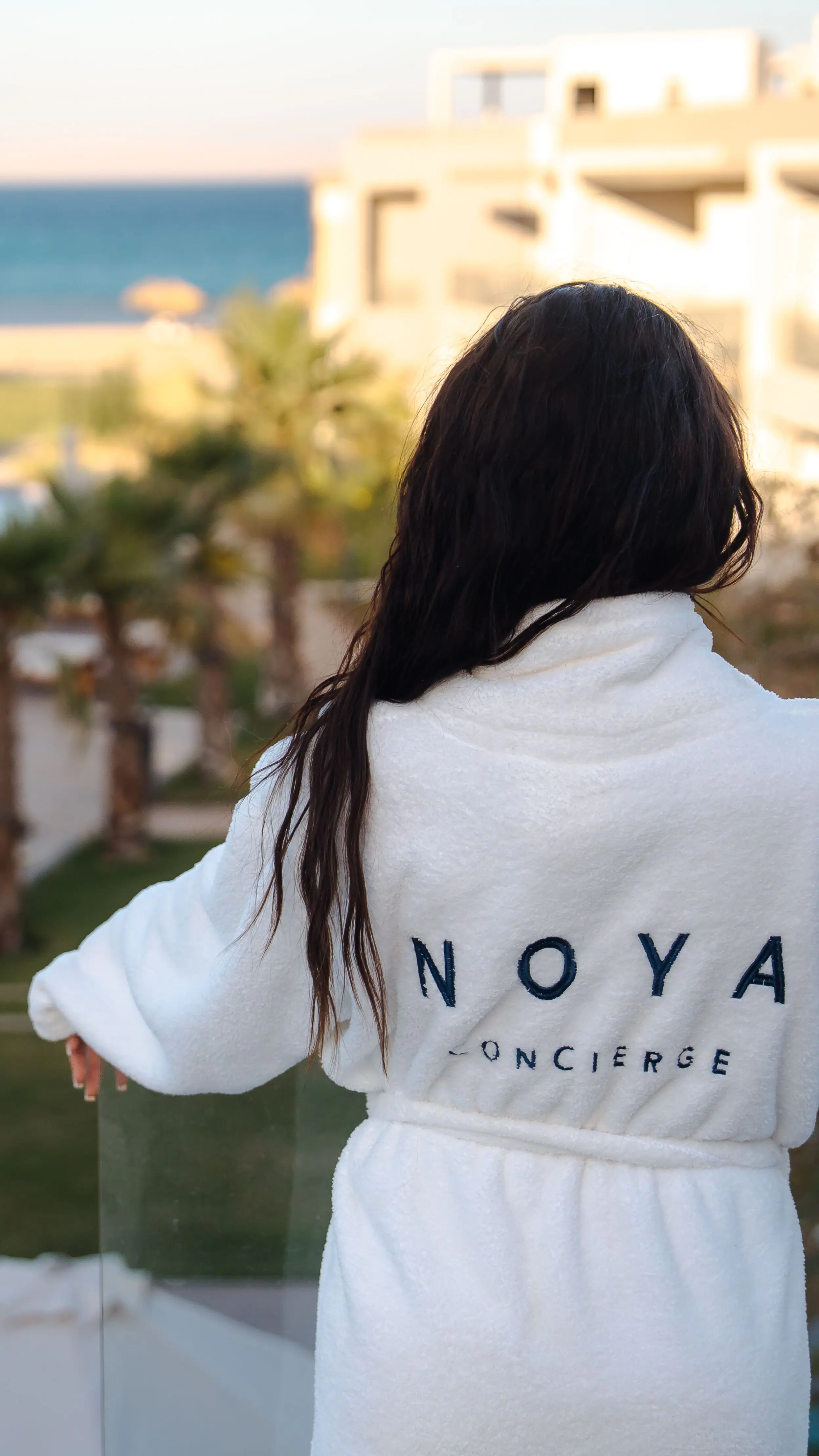 A guest in a NOYA robe on a terrace above a pool in El Gouna, looking out to the Red Sea