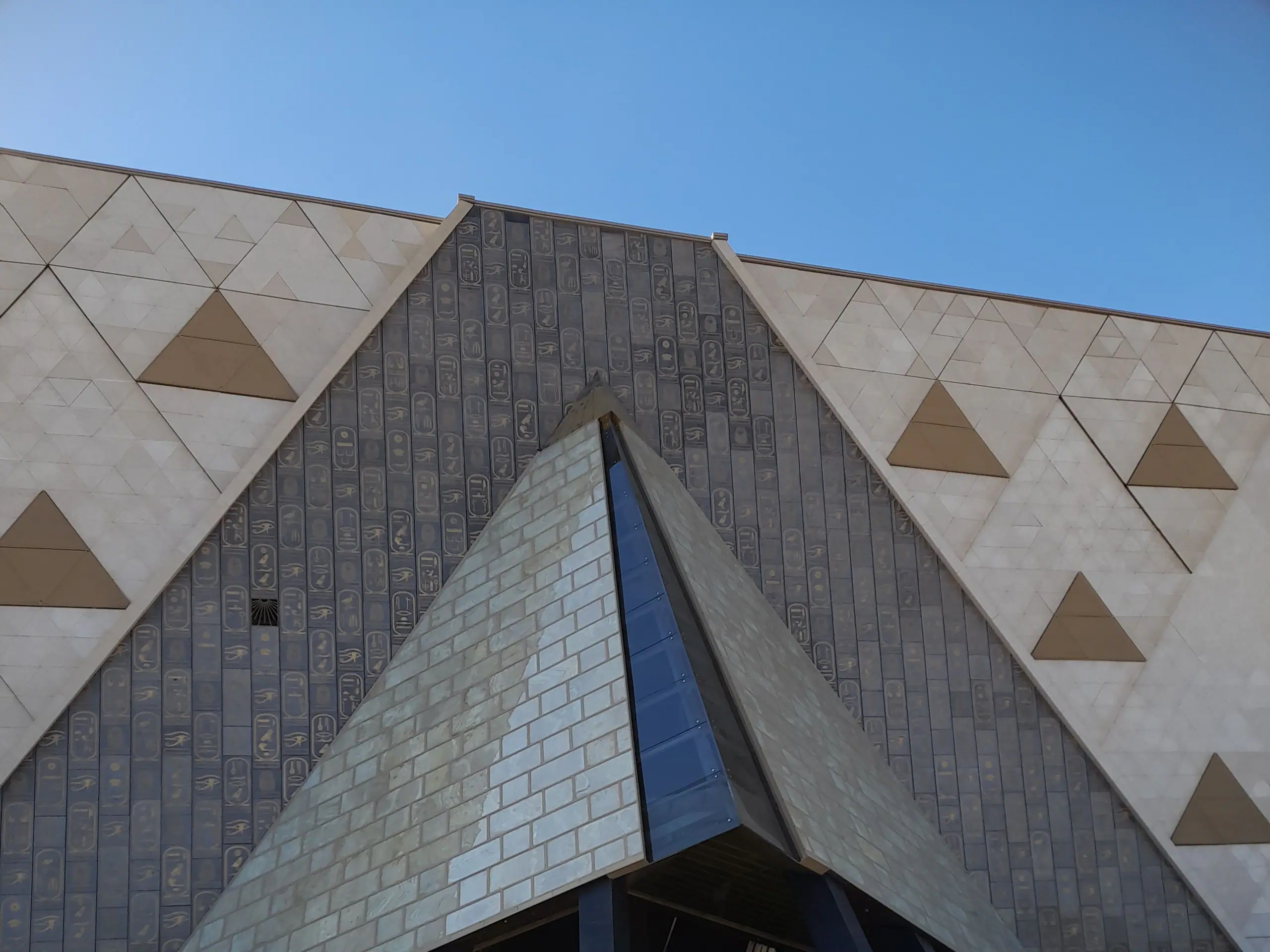 The pyramid-shaped entrance and hieroglyph-carved façade of the Grand Egyptian Museum
