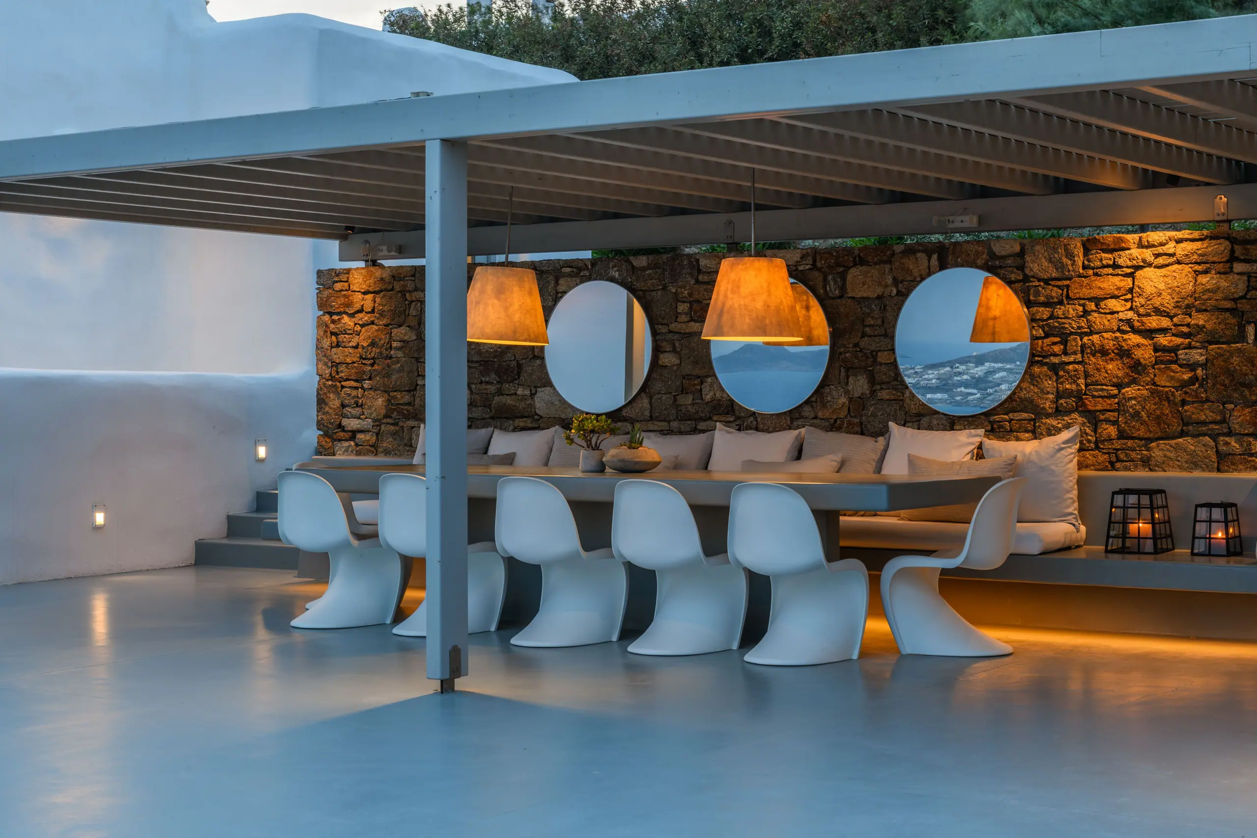A covered dining terrace at dusk above the Aegean