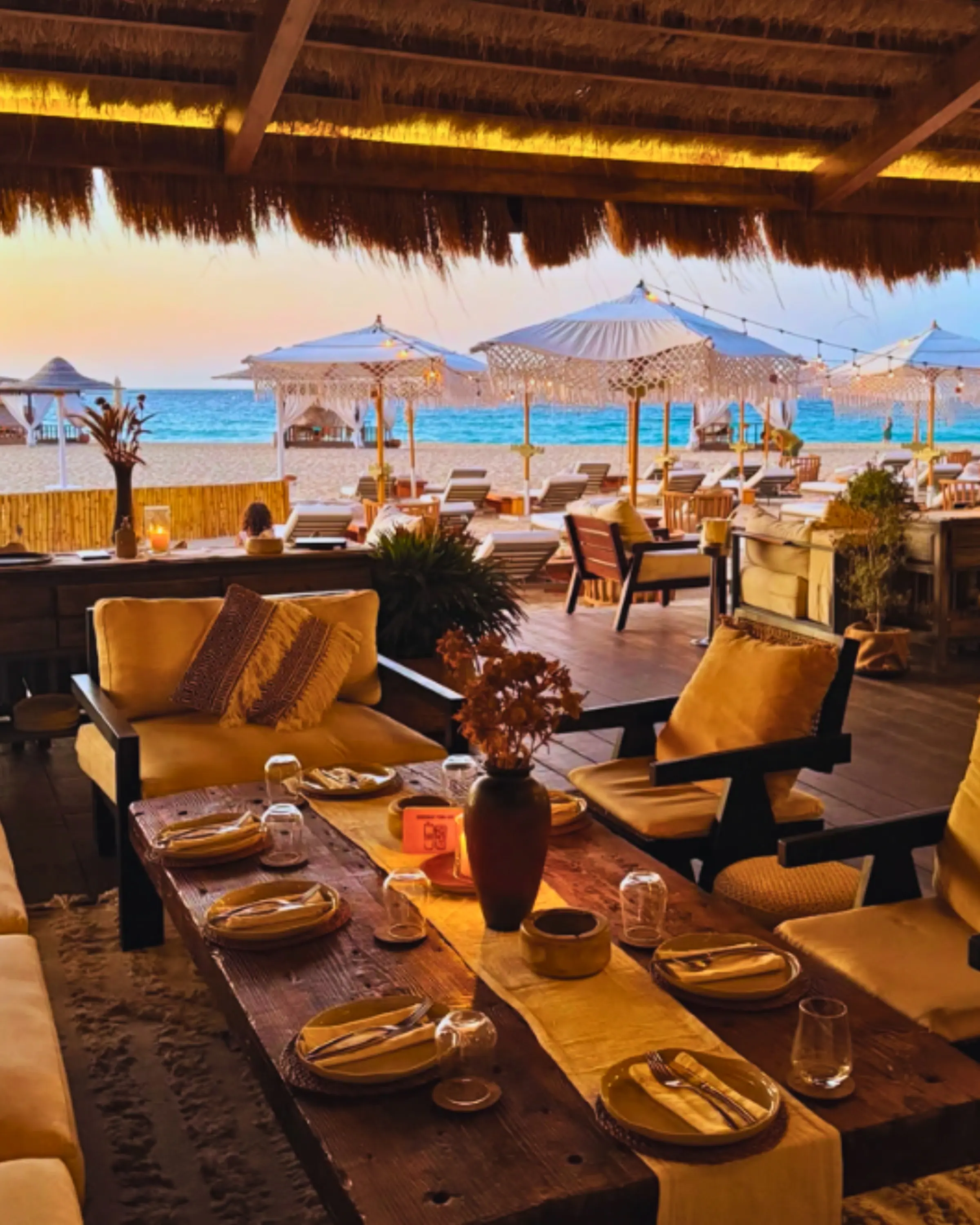 Low tables and loungers at a beach club at sunset
