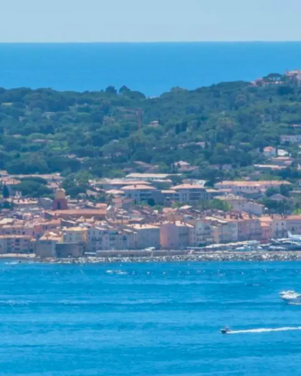 The old town and harbour of Saint-Tropez across the water, a speedboat’s wake in the bay