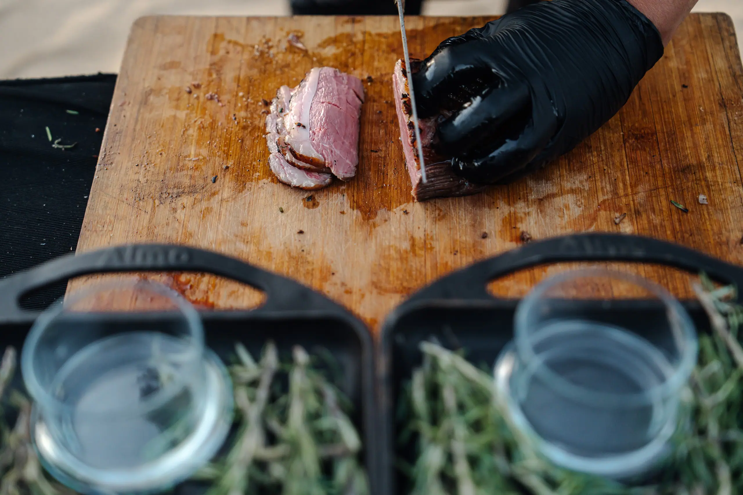A chef carving meat at a beach dinner