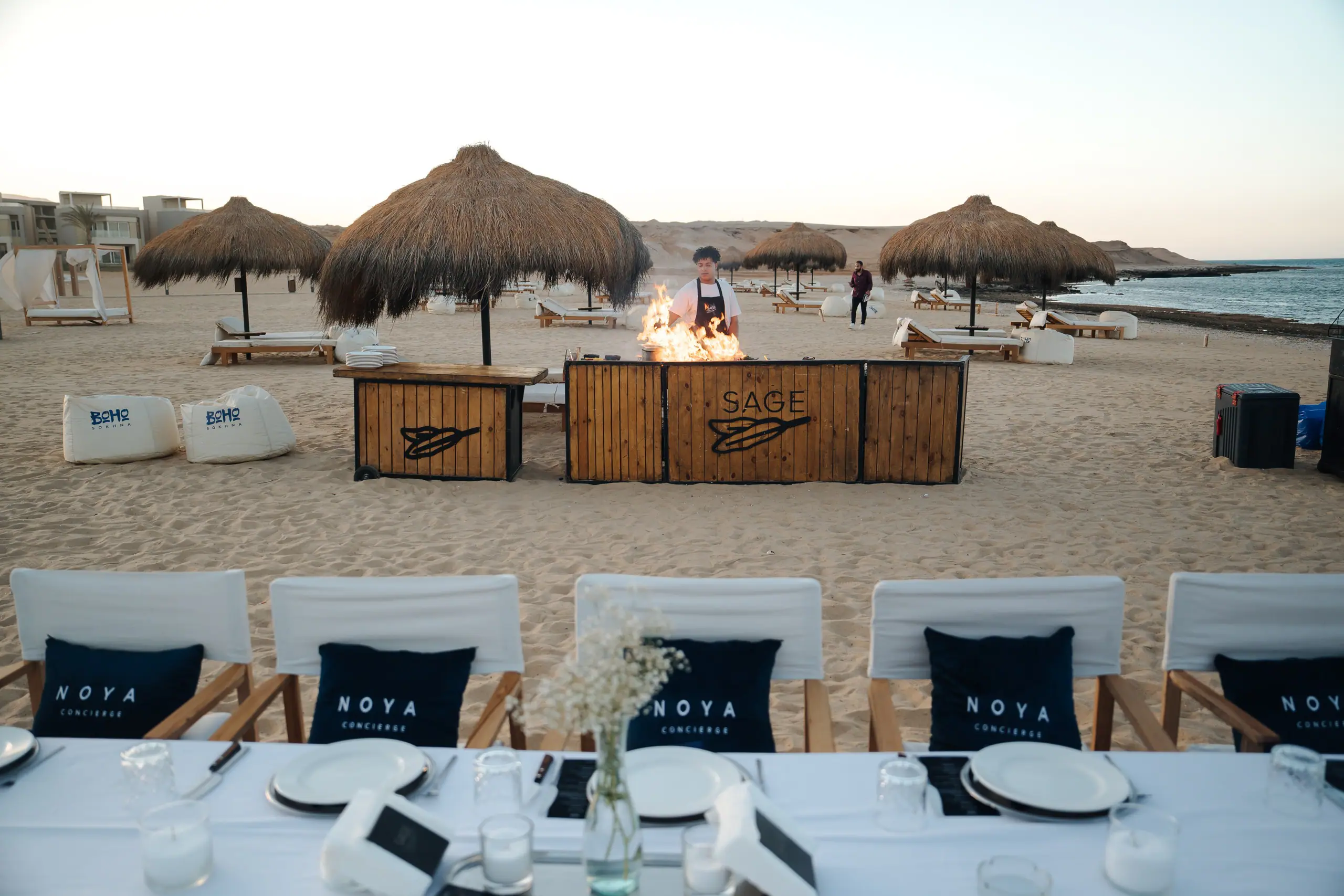 A beach dinner set up with NOYA cushions and a grill station