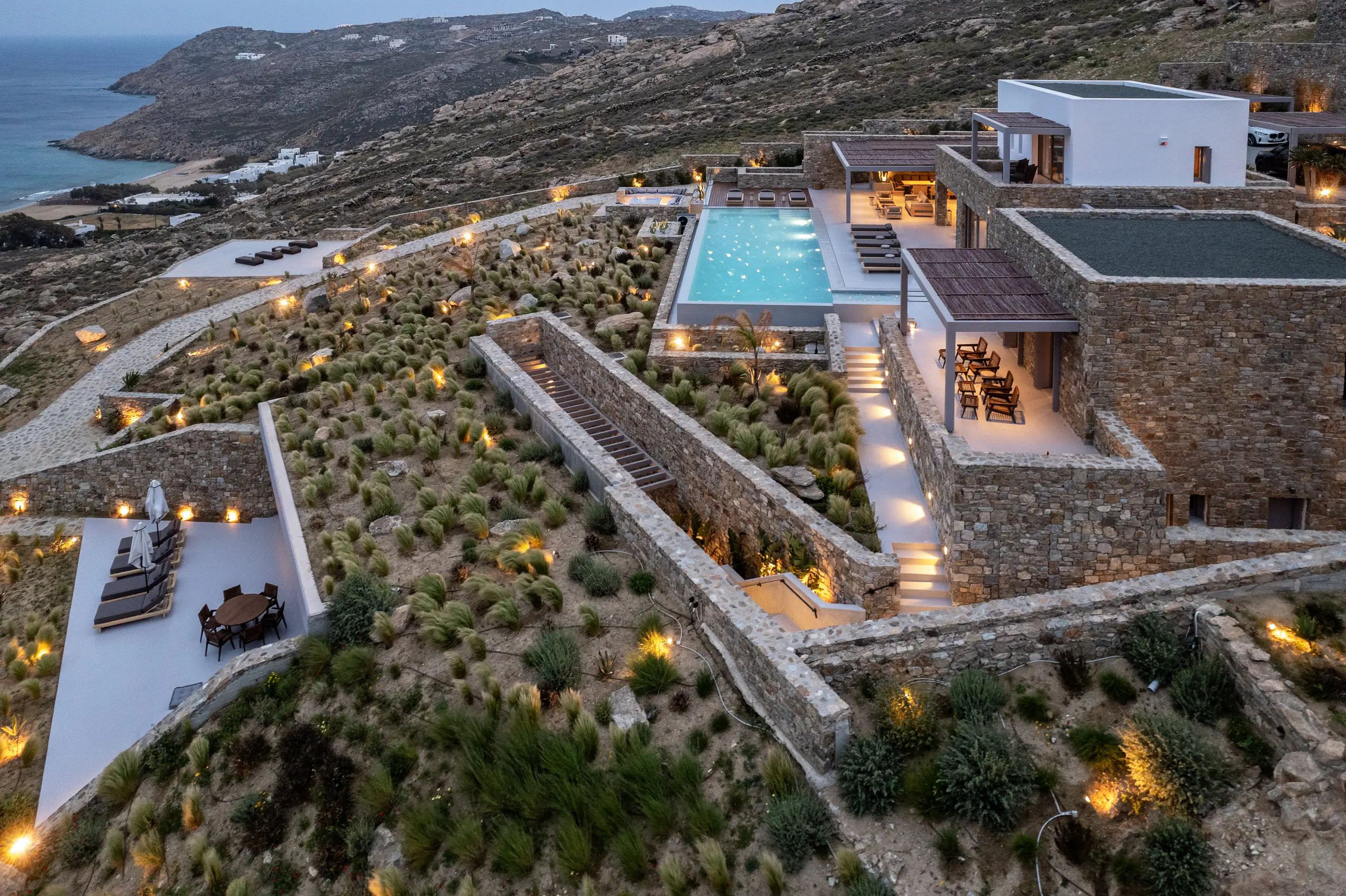 Villa Serenade lit at dusk on the hillside above Elia, Mykonos, with its pool and terraces
