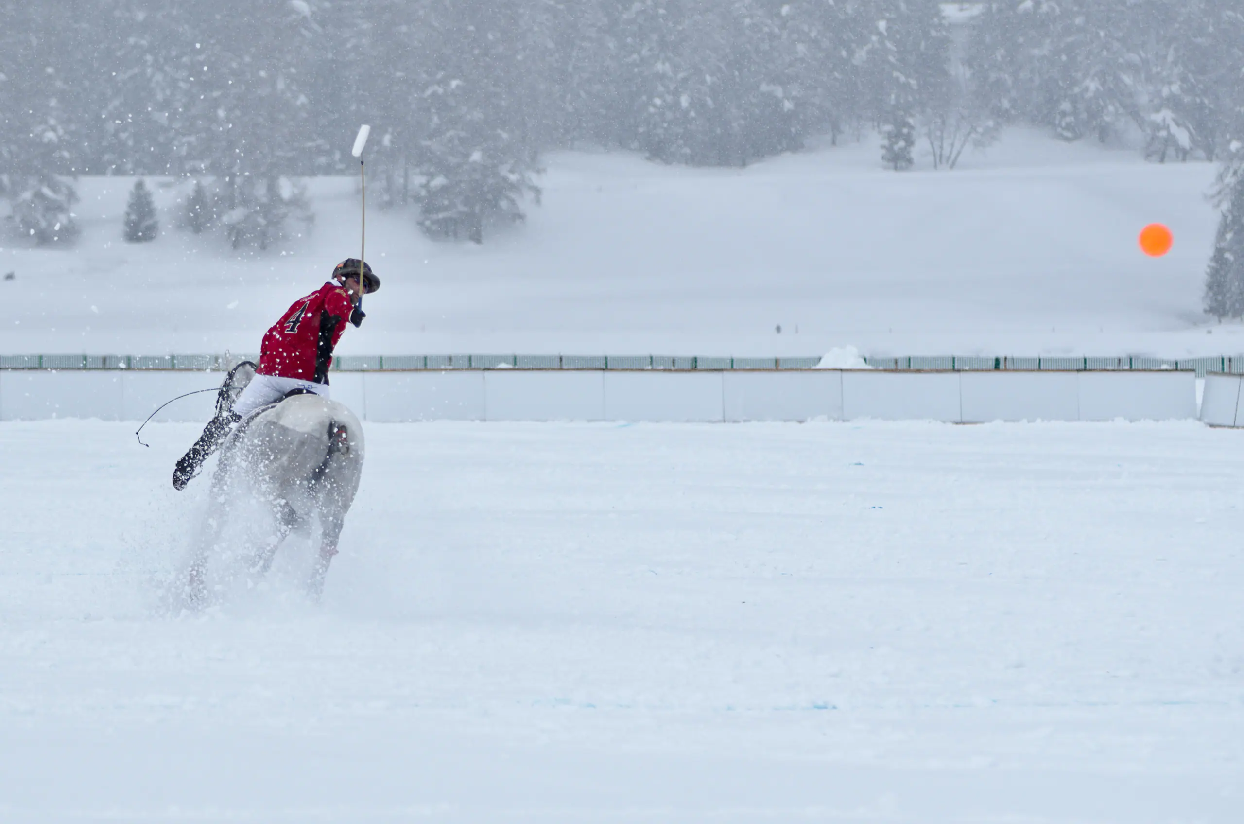 A polo player at full gallop in falling snow on the frozen lake at the Snow Polo World Cup, St. Moritz
